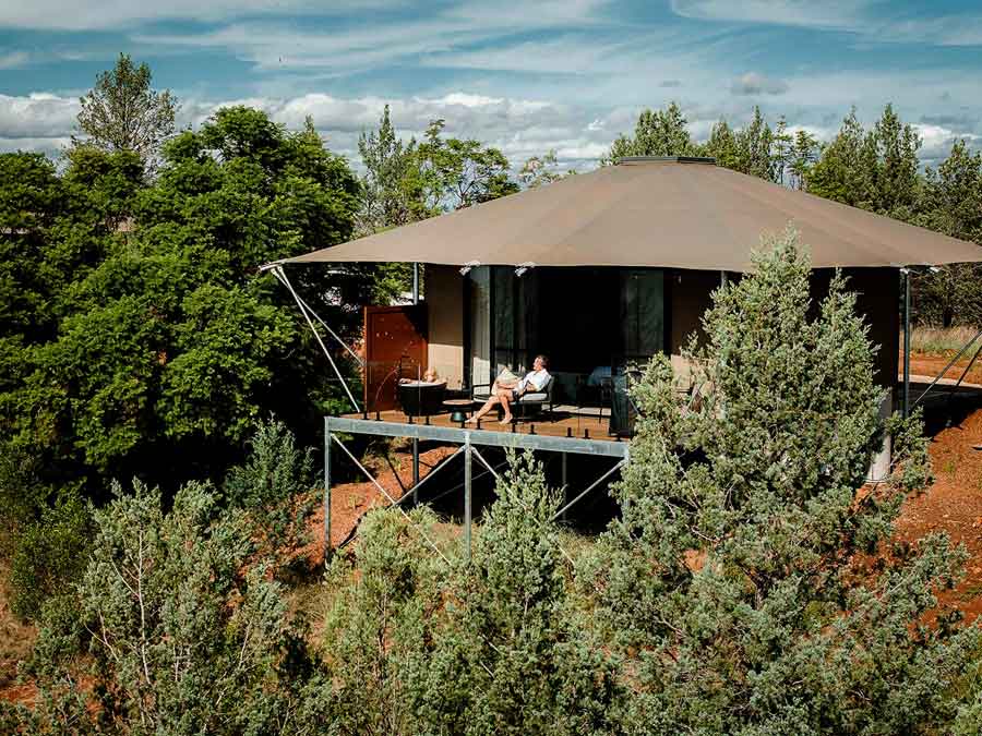 Wilderluxe-Deck-Lake-Keepit Image of a man relaxing on a chair on the deck of a glamping tent at Wilderluxe Lake Keepit